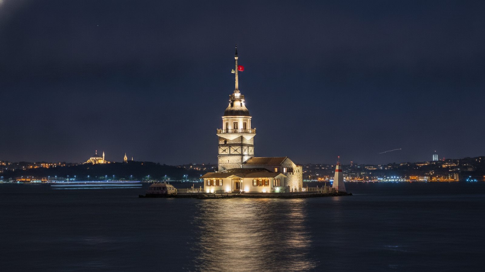 Maiden's Tower illuminated at night, its light reflected on the dark water of the Bosphorus